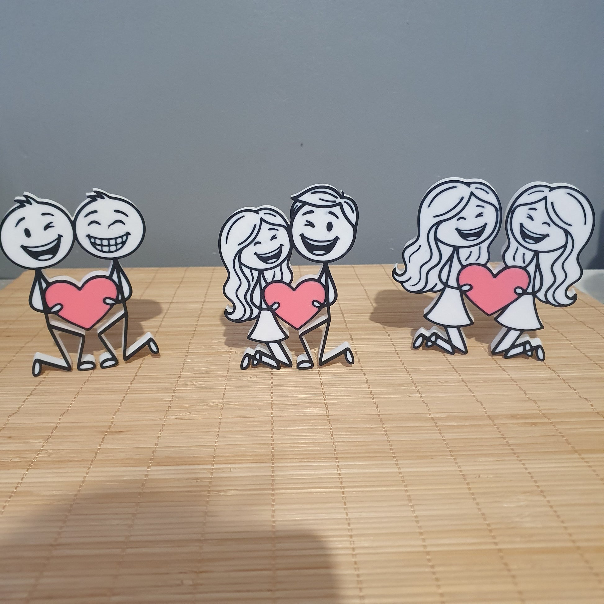 Présentation des trois modèles de couples inclusifs en 3D : homme-homme, homme-femme et femme-femme tenant un cœur rose.