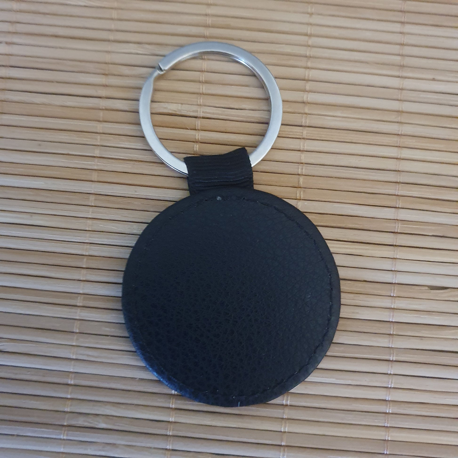 Dos du porte-clés aspect cuir noir avec coutures apparentes