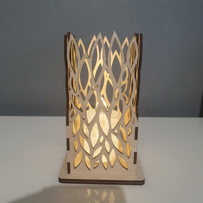 Photophore carré en bois avec motif de feuilles découpé au laser, éclairé par une bougie LED dans l'obscurité.